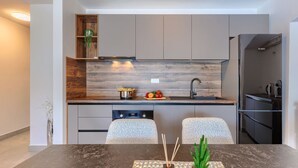 Une cuisine moderne avec un revêtement mural en bois, des appareils électroménagers en acier inoxydable et un coin repas comprenant une table et des chaises.