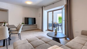 Un salon moderne doté d’un téléviseur à écran plat, d’un canapé, d’une table à manger et d’un balcon avec vue.