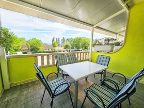 A covered outdoor seating area with a table and chairs, a railing, and a view of the surrounding area. - Apartment Dajak by Interhome (Omiš)