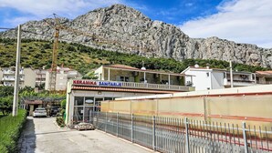 A building with a sign reading "KERAMIKA SANITARIJE" in front of a mountainous backdrop. - Apartment Dajak by Interhome (Omiš)