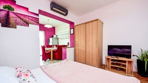 A bedroom with a bed, a TV, a wardrobe, and a desk with a chair. - Apartment Dajak by Interhome (Omiš)