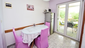 A dining area with a table and chairs, a refrigerator, a microwave, and a sliding glass door leading to an outdoor patio. - Apartment Dajak by Interhome (Omiš)