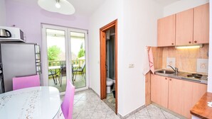 A compact kitchen with a refrigerator, a sink, and a dining area with a table and chairs. - Apartment Dajak by Interhome (Omiš)