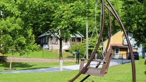 A swing set in a park with houses in the background.