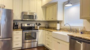 A modern kitchen with stainless steel appliances, white cabinetry, and a granite countertop.