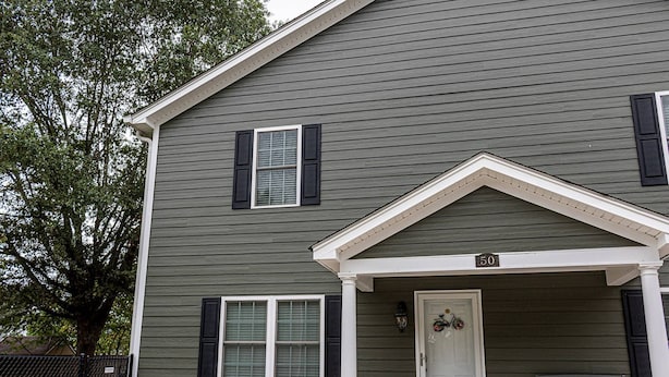 A two-story house with a front porch, a mailbox, and a number "50" sign.