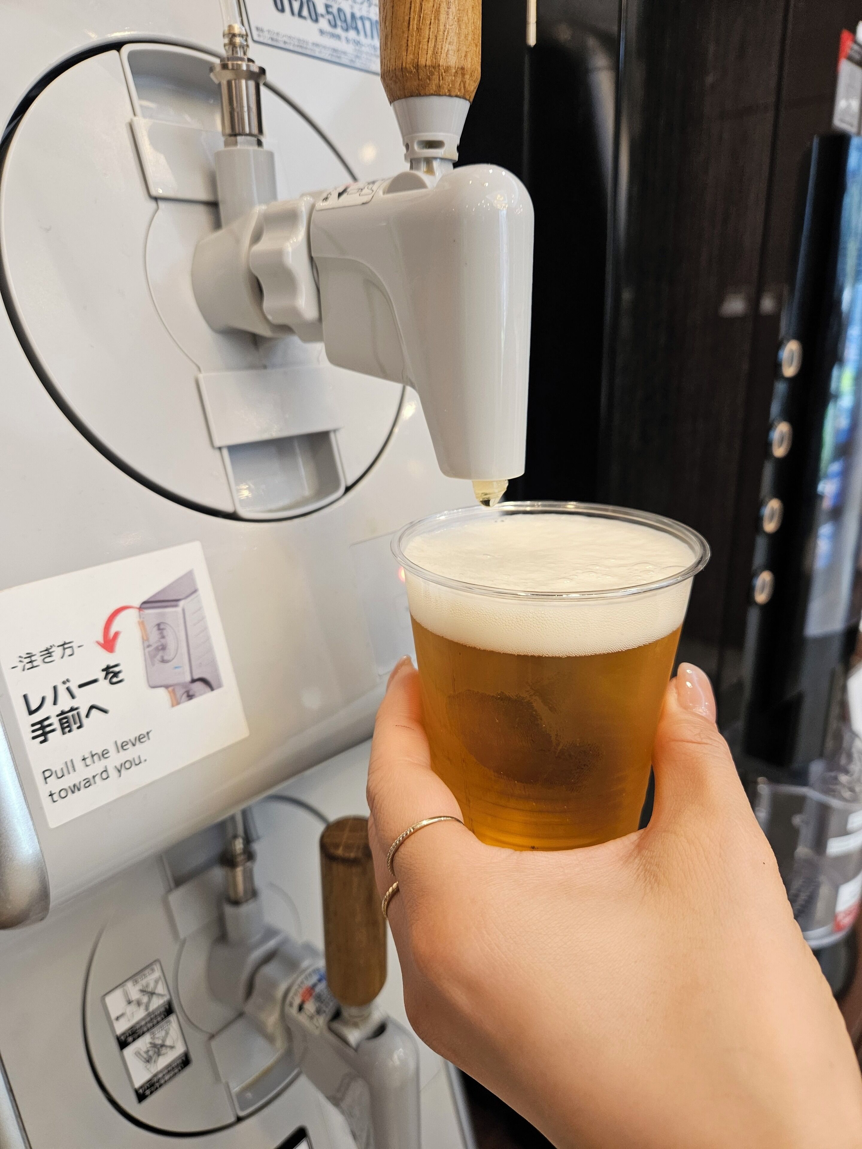 A hand holding a glass of beer being filled from a tap.