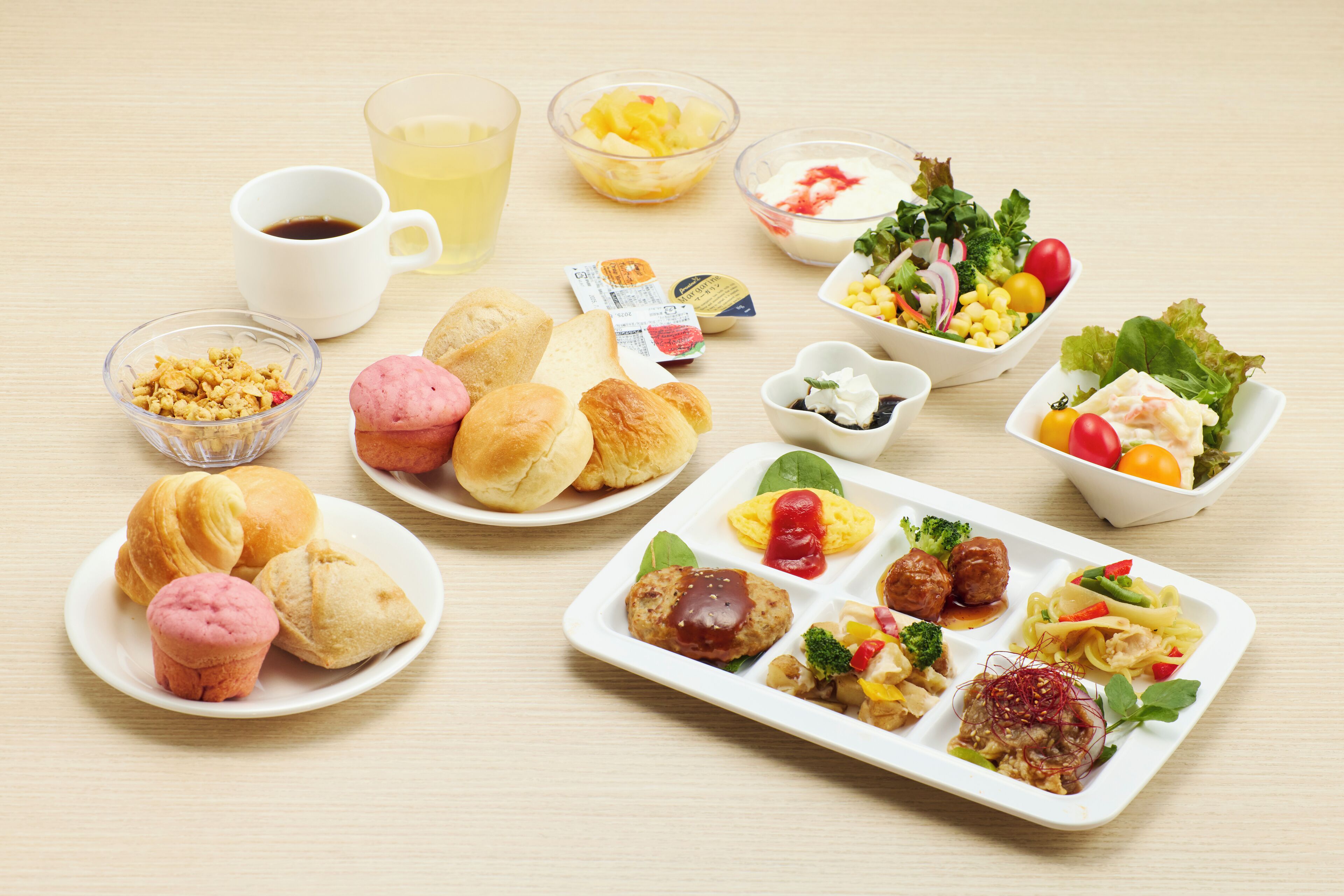 Une variété d’aliments, notamment des pâtisseries, des salades et un plat de viande, disposés sur une table.
