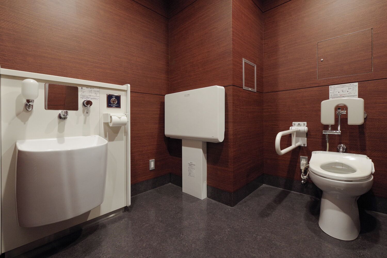 A restroom with a white sink, a toilet, and a urinal.