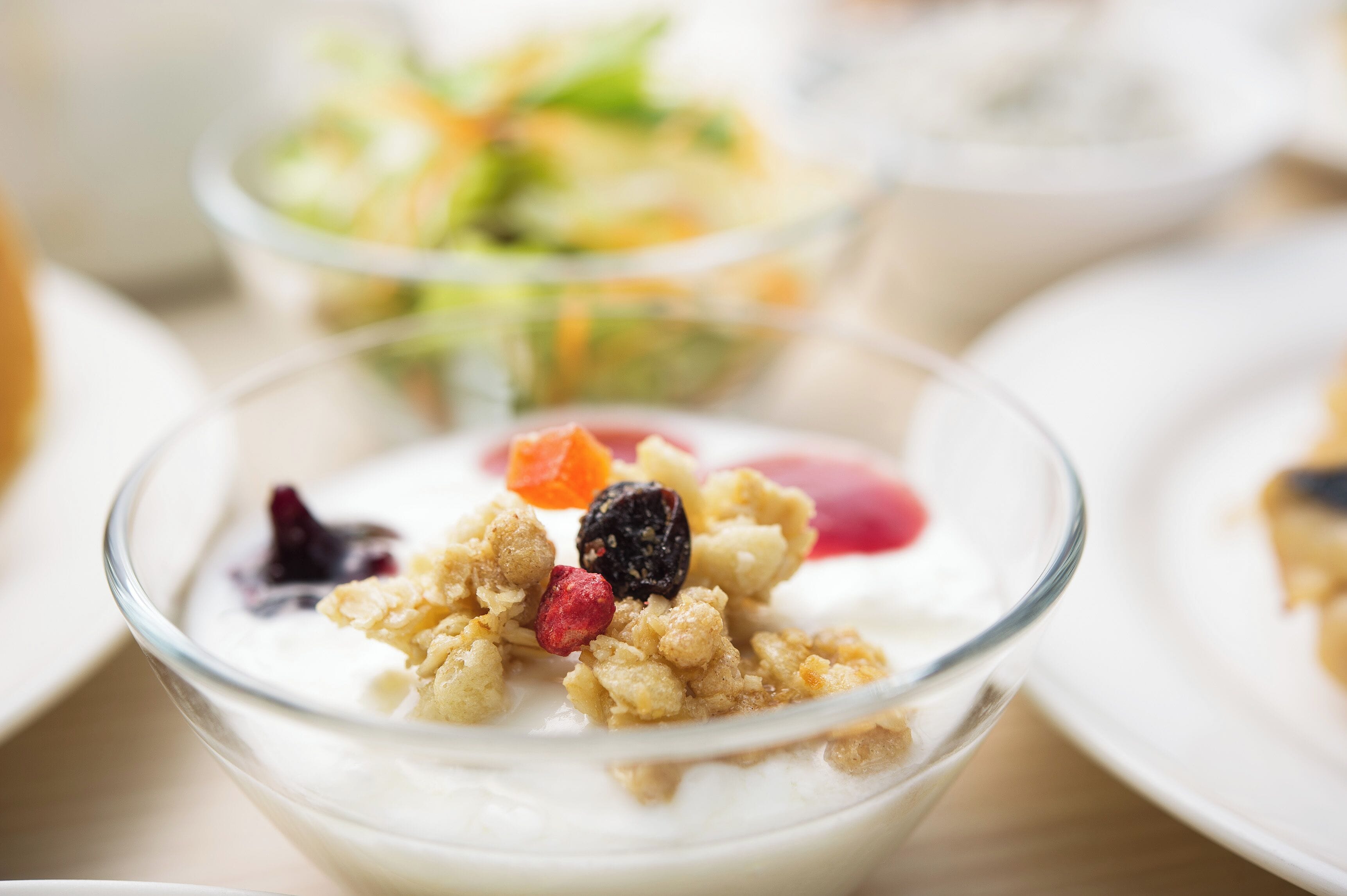 Primer plano de un bol de postre con yogur, granola y frutos rojos.