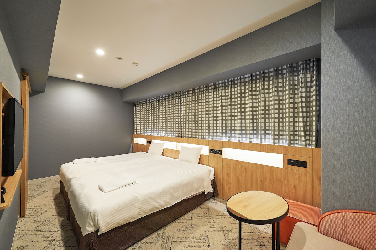 Una habitación de hotel moderna con una cama grande, una mesita redonda y un área de descanso.