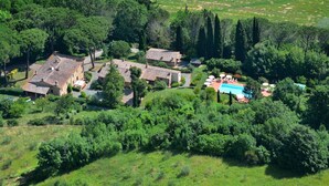 Una villa con diversi edifici, una piscina e vegetazione lussureggiante.