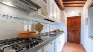 A kitchen with a gas stove, a wooden door, and a tiled backsplash. - POPULUS - Ground floor apartment of 115 m2 (Montaione)