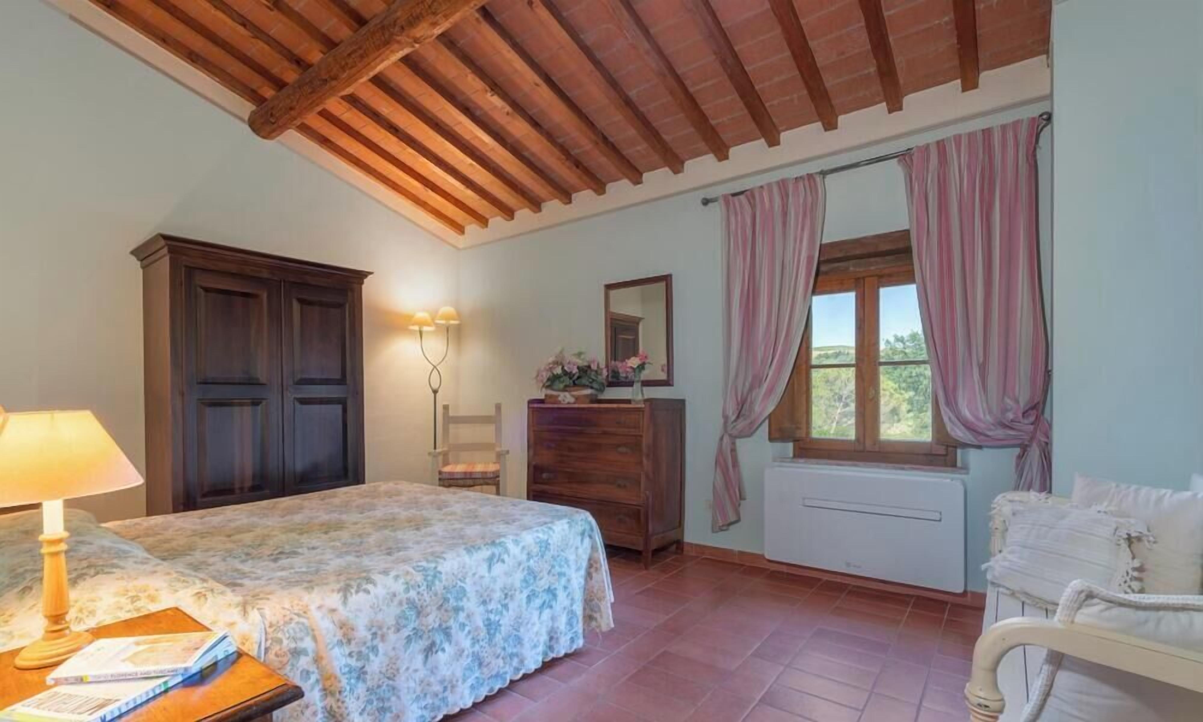 Un dormitorio con cama, cómoda y ventana con cortinas.