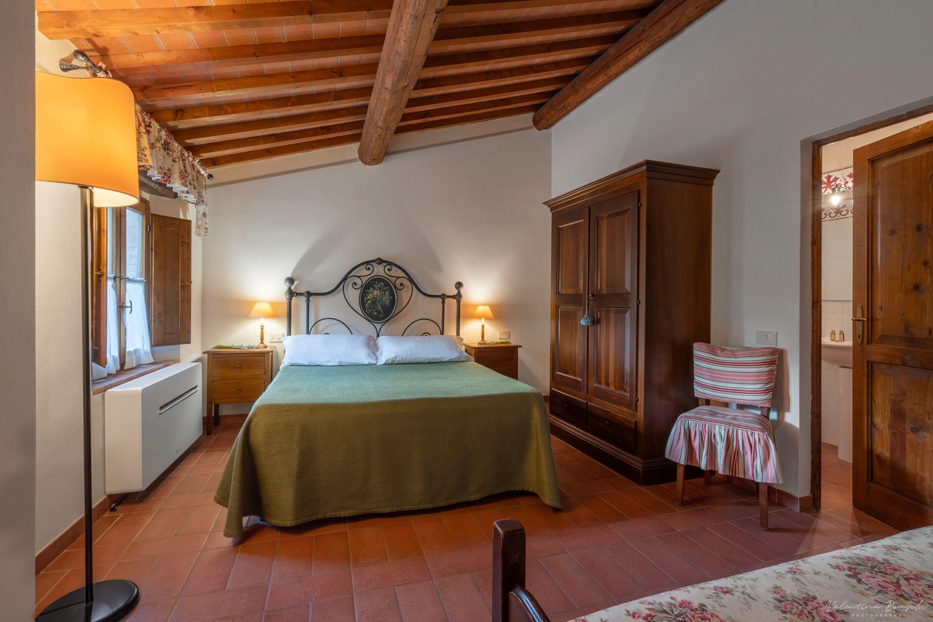 Une chambre à coucher avec un lit, une armoire en bois, une chaise et une lampe.