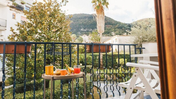 A balcony with a tray of breakfast items including a mug, banana, orange juice, and toast.