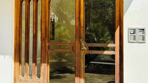 A wooden door with a glass panel and a metal intercom system.