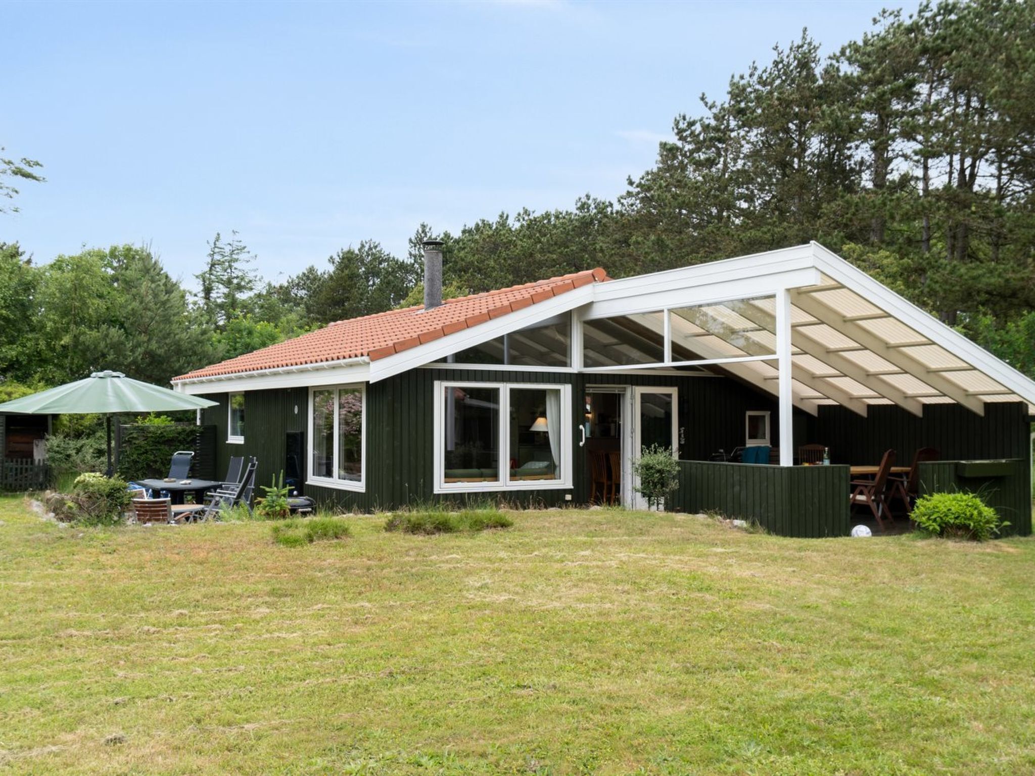 Una casa a un piano con tetto spiovente, ampie finestre e una veranda coperta.