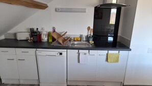 Een moderne keuken met witte kasten, een vaatwasser, een zwart fornuis en een raam.