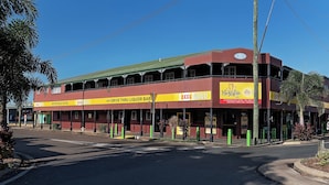 A two-story hotel with a red and yellow facade, multiple balconies, and a sign for 'Metropole Hotel'.