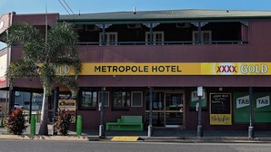 A hotel with a yellow sign reading "Metropole Hotel" and "XXXX Gold" on the facade.