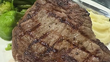 Un plato con carne, verduras verdes acompañadas de puré de papas.