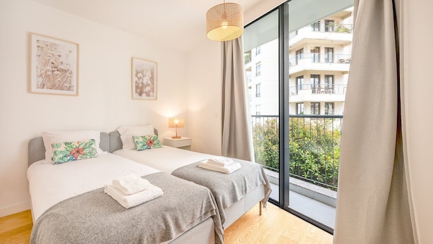 A modern bedroom with two beds, a large window, and a balcony view. - GuestReady - One prime stay in Campolide (Lisbon)