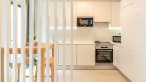 A modern kitchen with white cabinets, a Bosch microwave, and a built-in oven. - GuestReady - One prime stay in Campolide (Lisbon)
