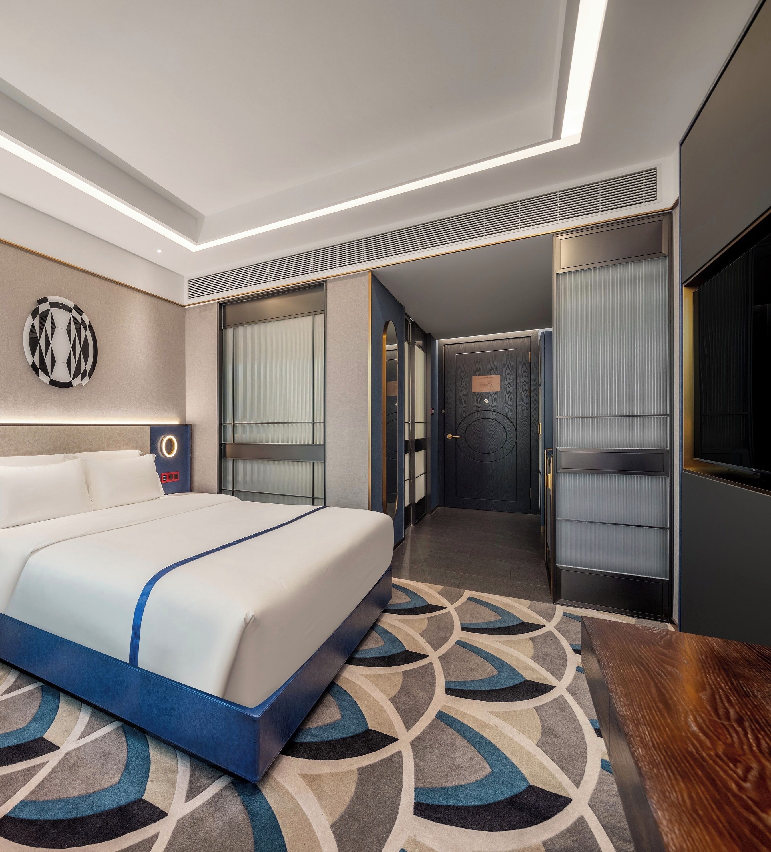 Una habitació d'hotel moderna amb un llit gran, un escriptori i un armari encastat.