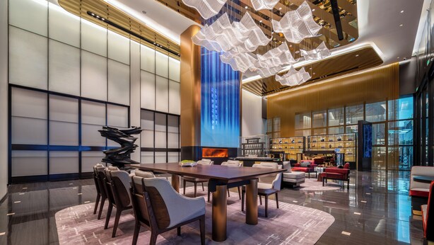 A modern hotel lobby with a large reception desk, seating area, and a unique ceiling design. - Xi'an Zhonglou Fengdu Hotel (Yongxingfang Changlemen Subway Station Branch) (Xi'an)