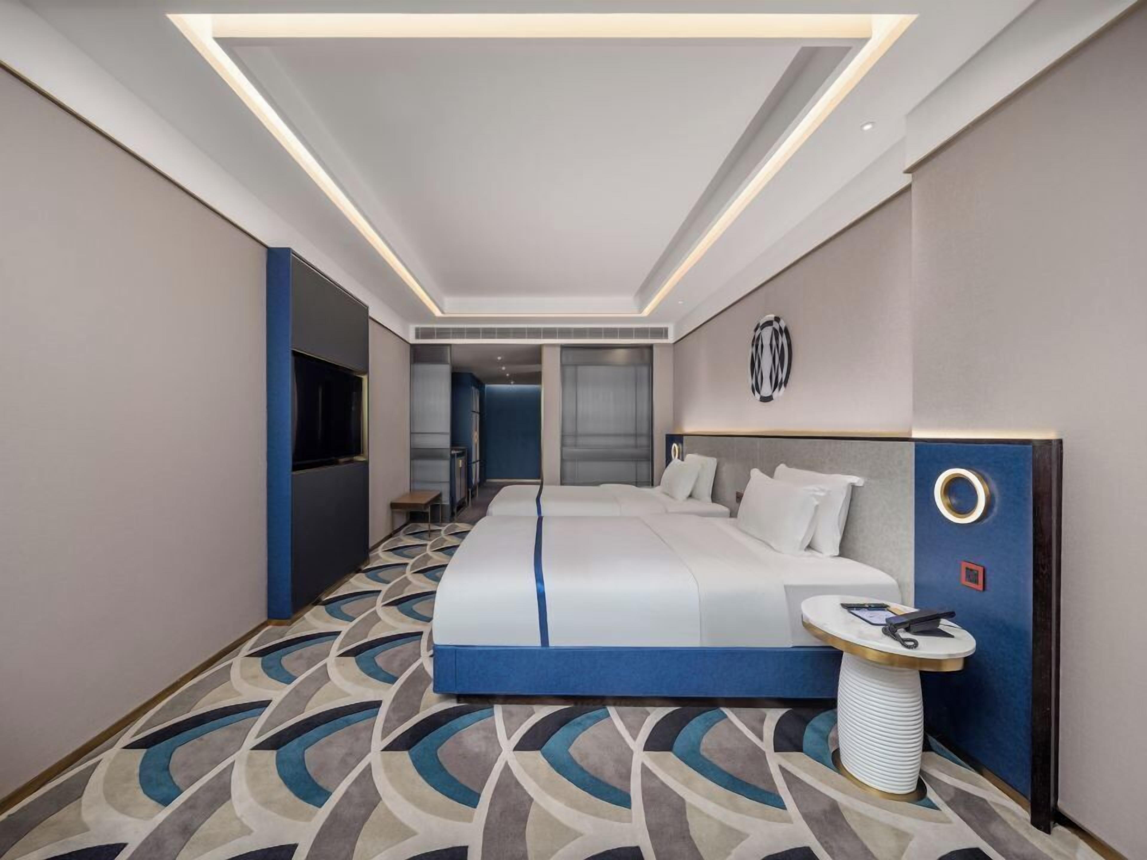 Ein modernes Hotelzimmer mit einem großen Bett, einem Nachttisch und einem Fernseher.