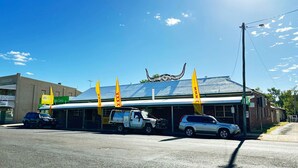 A building with a metal roof, a signboard, and a flag. - Charleville Cattle Camp Hotel  (Charleville)
