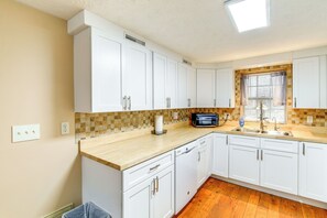 A kitchen with white cabinets, a wooden countertop, a microwave, and a window with curtains. - Peaceful South Holston Lake Cabin w/ Dock & Deck! (Abingdon)