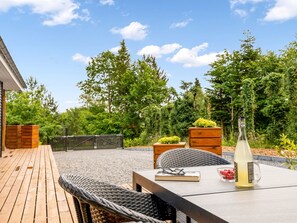 Relax in a serene outdoor space surrounded by lush greenery and trees, perfect for reading or enjoying a quiet moment.