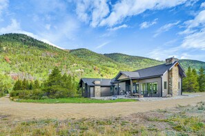 Ein modernes Haus mit Natursteinfassade, großen Fenstern und einer Terrassenfläche.