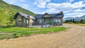 Een modern huis met twee verdiepingen, een grindpad, grote ramen en een terras.