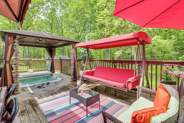 An outdoor deck with a hot tub, a swing, and a covered seating area.