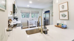 A modern kitchen with white cabinetry, a stainless steel sink, and a large window. - Modern Hilton Head Island Villa w/ Pool Access! (Hilton Head Island)