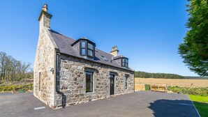 A stone house with a sloped roof, two chimneys, and a paved driveway. - Kirkton Family Farmhouse With Hot Tub Alford Aberdeenshire (Alford)