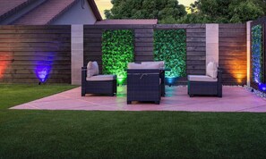 An outdoor patio with two wicker chairs, a small table, and a vertical garden wall.