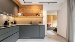 Una cocina moderna con un muro de acento de madera, una isla integrada y vistas a una sala de estar con sofá y cortinas.