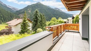 Un balcón con vista a montañas y una casa.