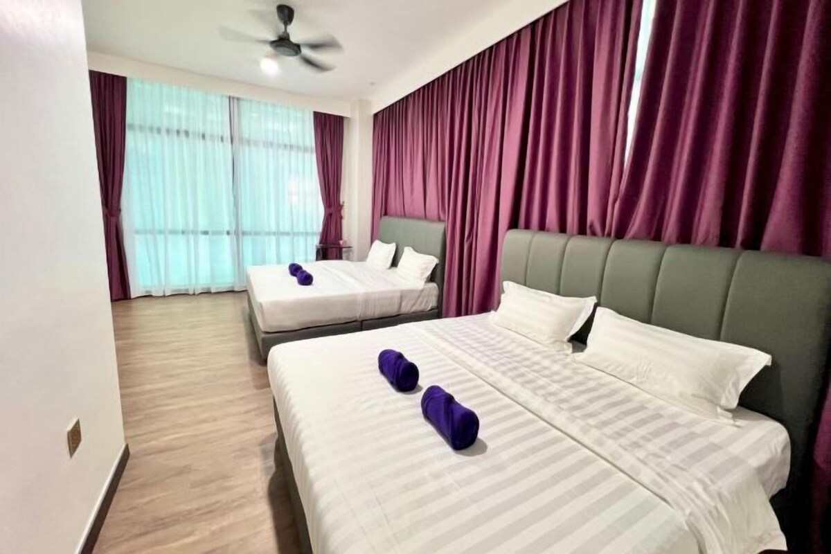 Une chambre d’hôtel avec deux lits, un ventilateur de plafond et de grandes fenêtres avec des rideaux.