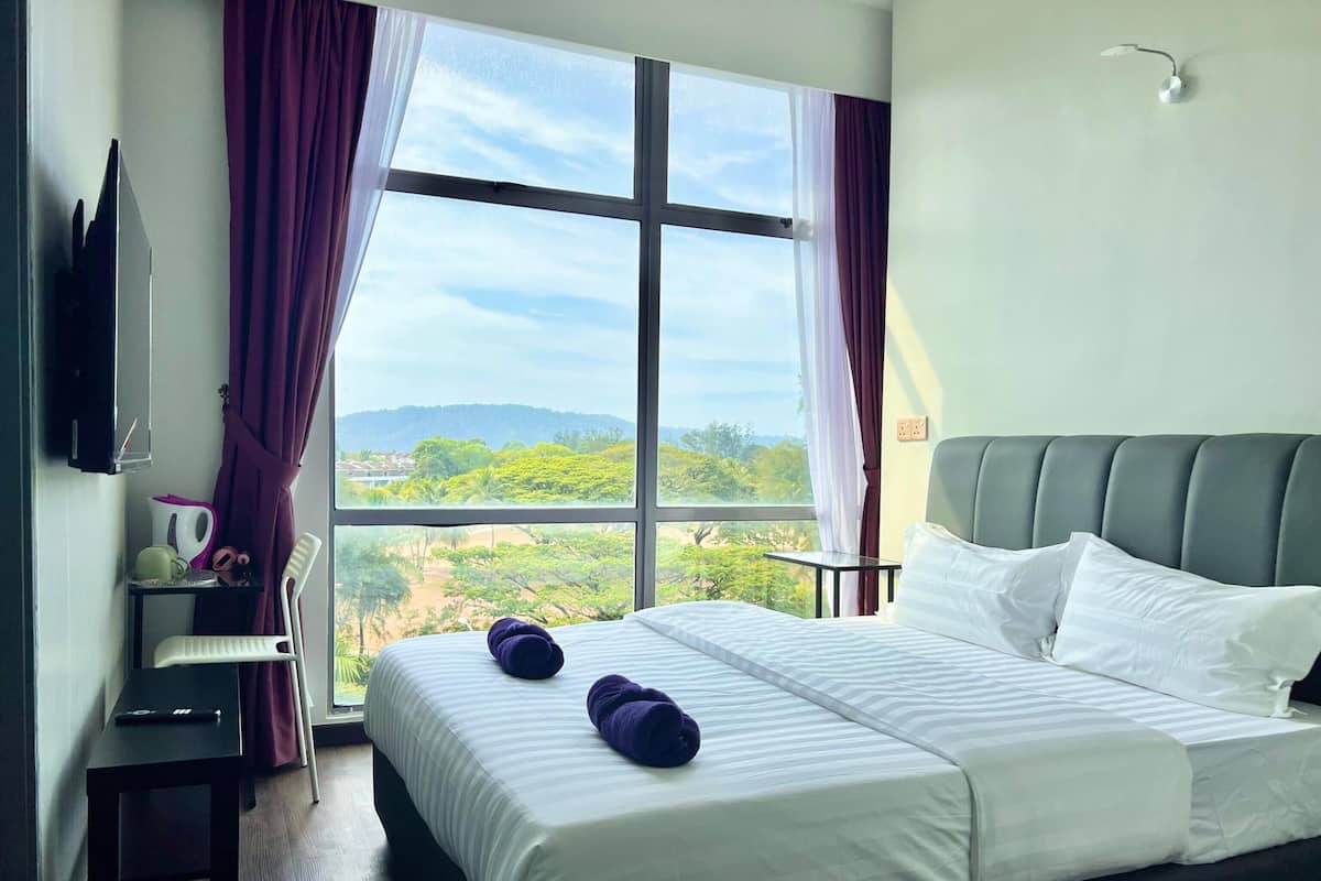 Une chambre d’hôtel avec un grand lit, un bureau, une chaise et un téléviseur fixé au mur.