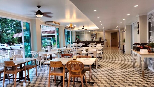 Un restaurante espacioso con suelo a cuadros, varias mesas y sillas, y grandes ventanales que ofrecen vistas al exterior.