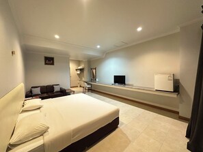 A hotel room with a bed, a desk with a computer, a chair, a small table, and a TV. - Rattanaview Hotel (Phitsanulok)