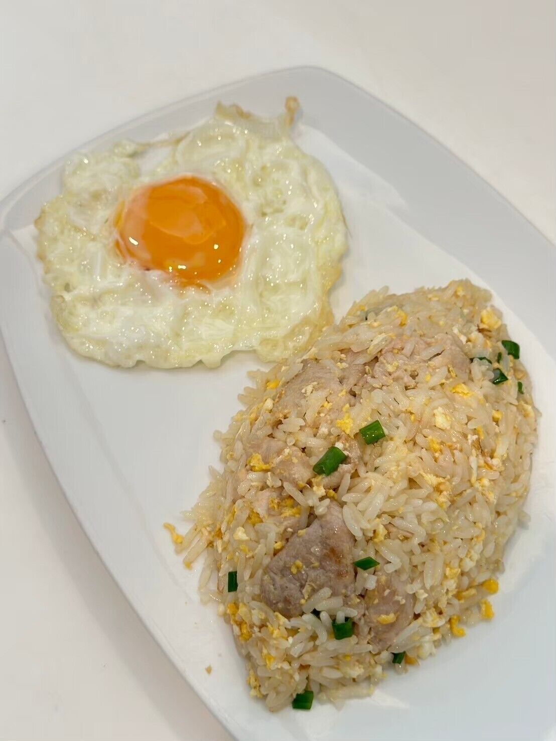 A plate of fried rice with meat and scrambled eggs, and a fried egg on the side.