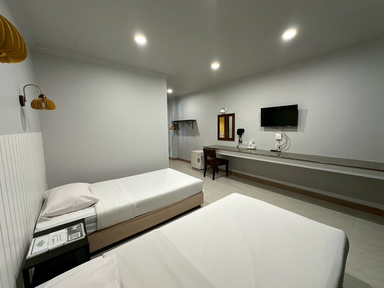 Habitació d'hotel amb dos llits individuals, una taula de nit amb cadira, televisió de pantalla plana penjada a la paret i un telèfon.