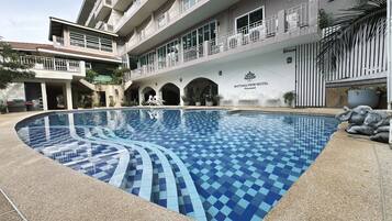 Un hotel con piscina, varios balcones y un cartel con el nombre del hotel.