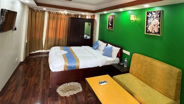 A hotel room with a bed, a sofa, a small table, and a green accent wall. - Charming Durbar Hotel  (Kathmandu)